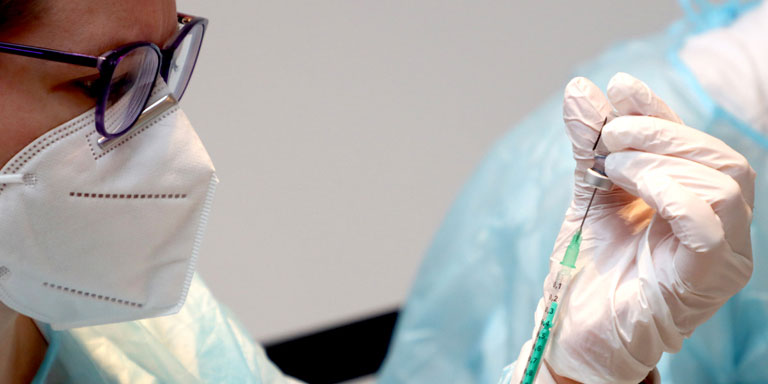 Il medico preleva la dose di vaccino con una siringa