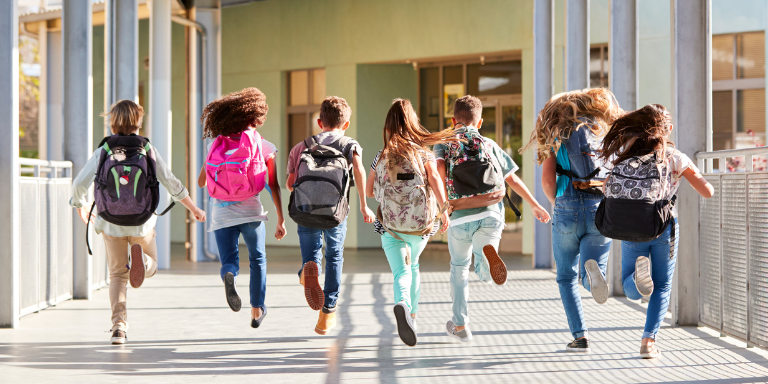 Sieben Kinder rennen auf einem Schulgelände