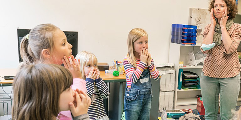 Kinder stehen mit Schulungsleiterin in einem Kreis