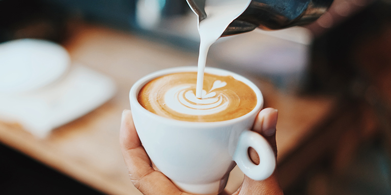 Frische Milch wird in einen Kaffee gegeben