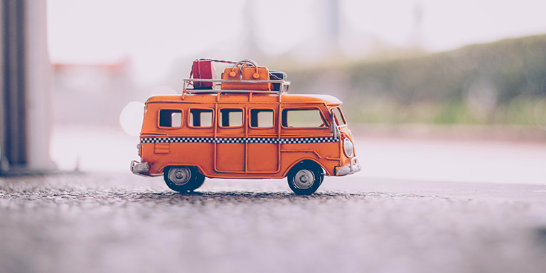 Oranger Spielzeugbus mit Gepäck auf dem Dach