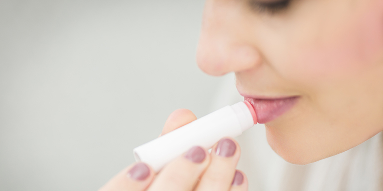 Une femme utilise un stick de soin pour les lèvres