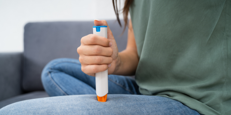 Une femme utilise un auto-injecteur d’adrénaline sur sa cuisse.