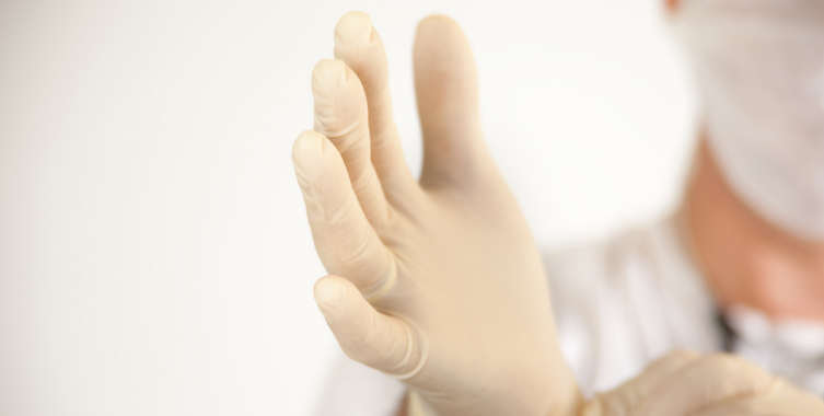 Medical professional puts on a latex glove.