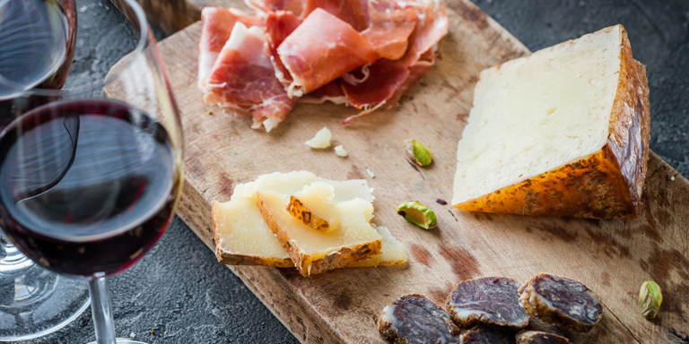 Wine, bread and platter with meat and cheese