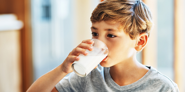 A boy drinks a glass of milk