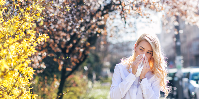 Spring, flowering bush, woman blowing her nose