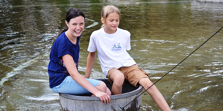 Zwei Mädchen spielen draussen am Wasser