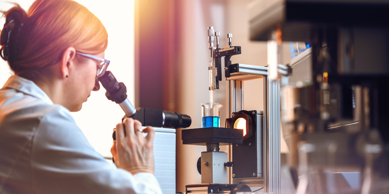 Une femme au microscope dans un laboratoire.