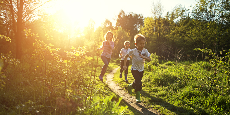 Bambini che corrono su un sentiero nel bosco.