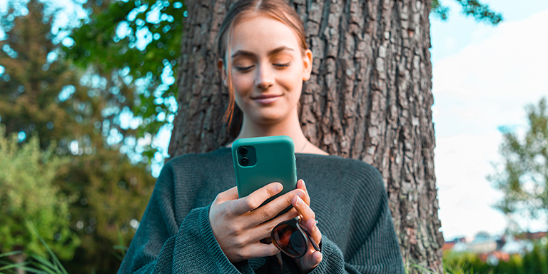 Ragazza che guarda il telefono cellulare fuori