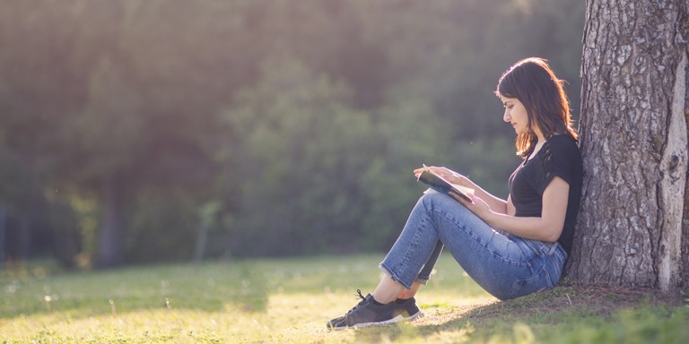 Une jeune femme lit un livre dehors