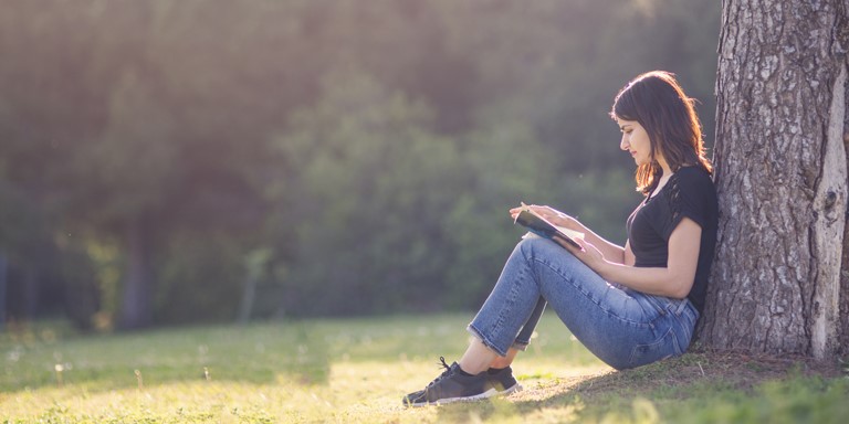 Giovane donna che legge un libro fuori