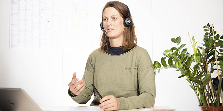 Une collaboratrice enjouée de aha ! Centre d'Allergie Suisse avec des écouteurs donne des informations.