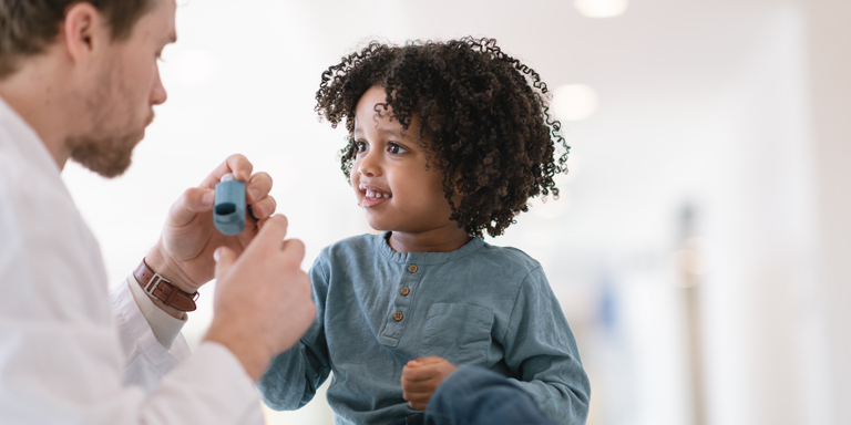 Un médecin apprend à un enfant à inhaler.