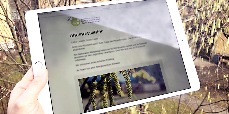 Jemand hält ein Tablet in der Hand, mit offener Anmeldeseite für den Newsletter.