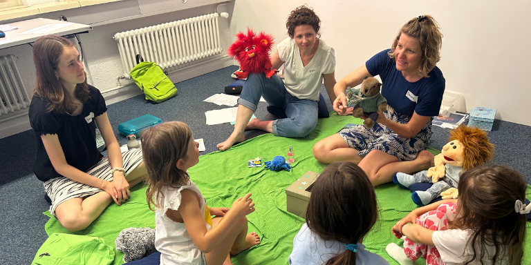 Kinder sitzen im Kreis und hören der Referentin zu.