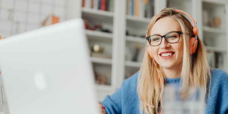 Eine Frau nimmt an einem Webinar teil und sitzt vor dem Laptop.