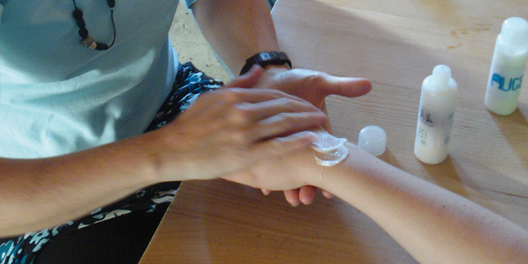 Eine Mutter cremt den Arm des Kindes ein.