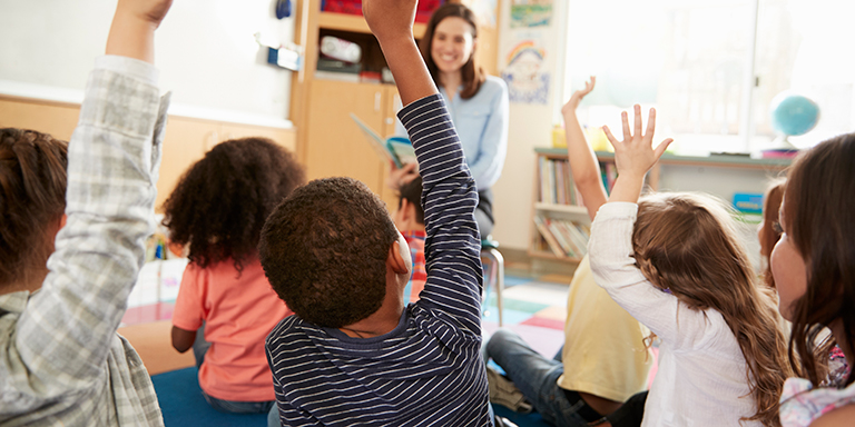 Blick in eine fröhliche, aufmerksame Runde Kinder in einem Kindergarten.