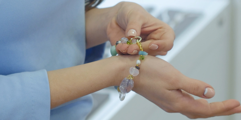 Détail de l'image : mains d'une femme toilettée ; un bracelet. La femme joue avec.