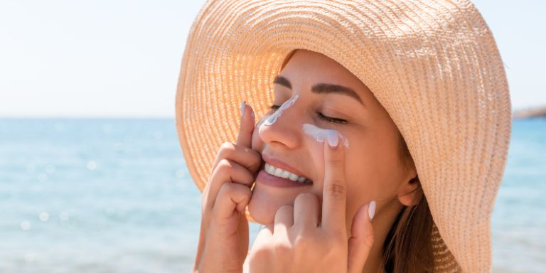 A woman is applying sunscreen to her face.