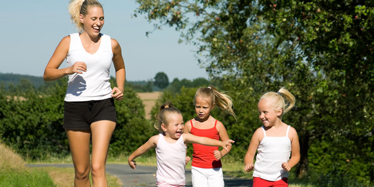 Femme avec ses enfants, faisant jogging dans la campagne.