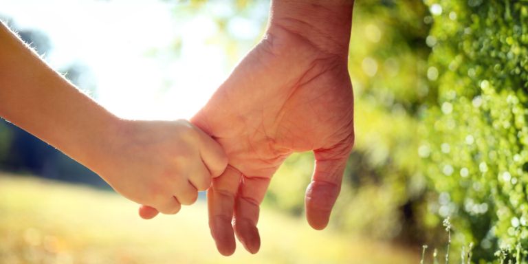 Une personne tient la main d'un enfant