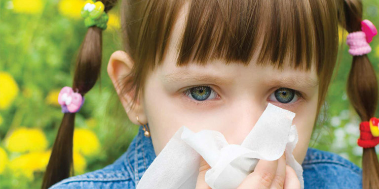 Ragazza Nina con allergia al polline starnutisce in un fazzoletto