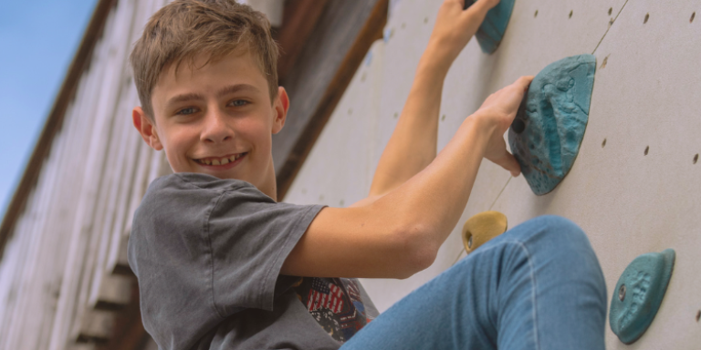 Ein Junge klettert im aha!sommerlager an einer Kletterwand.