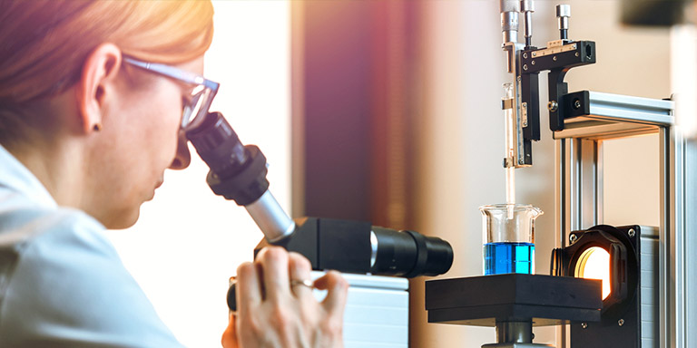 Une femme fait des recherches et regarde au microscope