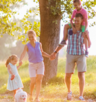 Eine Familie spaziert mit ihrem Hund fröhlich durch den Wald.
