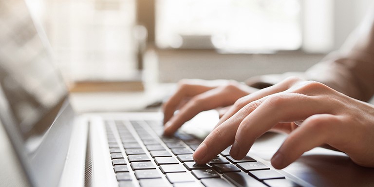 A person is writing on a laptop keyboard.