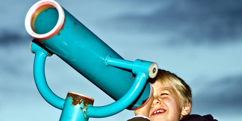 A boy looks through blue binoculars
